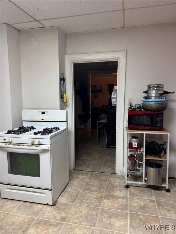 kitchen featuring a paneled ceiling and gas range gas stove