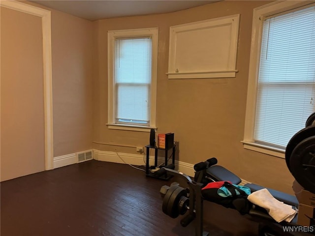 workout room featuring dark wood-style floors, baseboards, and visible vents