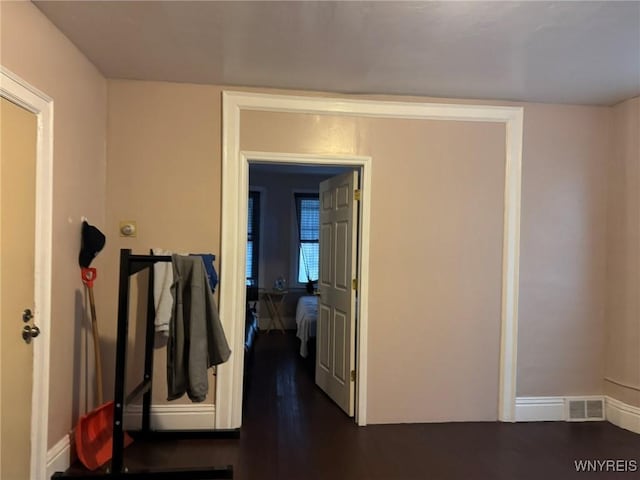 hallway featuring baseboards, visible vents, and dark wood-style floors