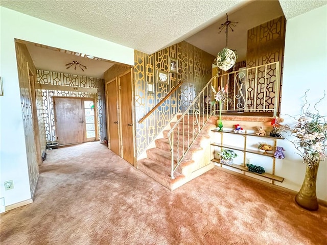 stairway featuring baseboards, carpet flooring, and a textured ceiling