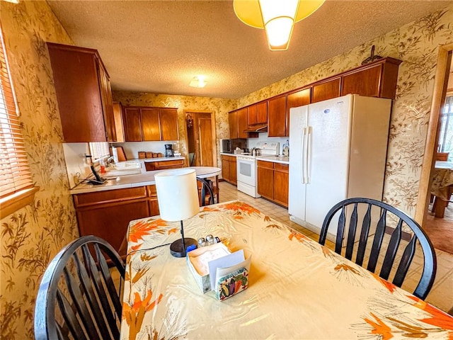 kitchen with wallpapered walls, light countertops, white appliances, and under cabinet range hood