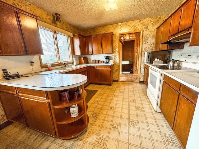 kitchen featuring wallpapered walls, light floors, light countertops, under cabinet range hood, and white range with electric stovetop
