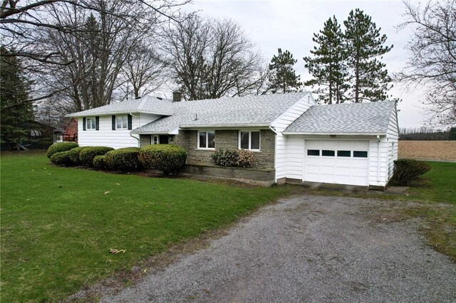 split level home with driveway, roof with shingles, a front yard, and a garage