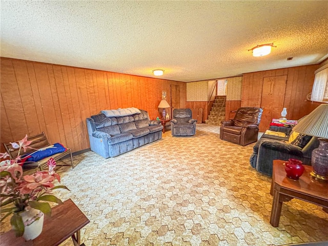 living room featuring wooden walls, a textured ceiling, and stairs