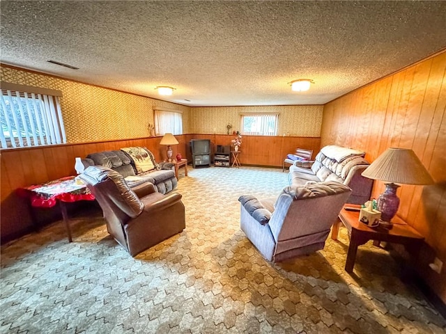 living area featuring wood walls, carpet floors, a textured ceiling, and visible vents