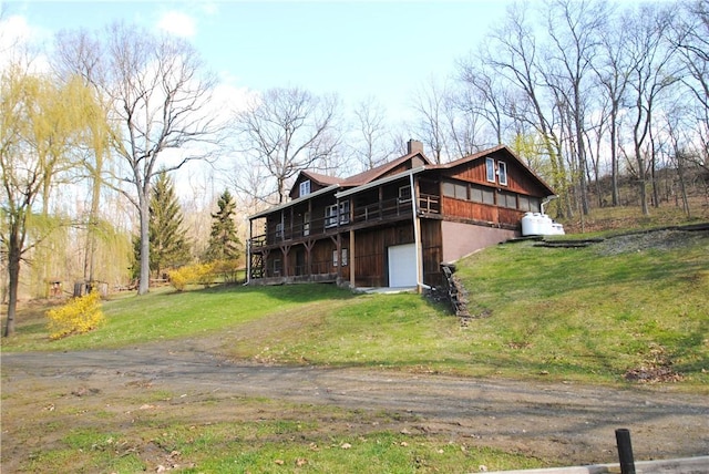 9221 Health St, North Dansville, NY 14437 - view of property exterior featuring driveway, a chimney, a lawn, a deck, and an attached garage