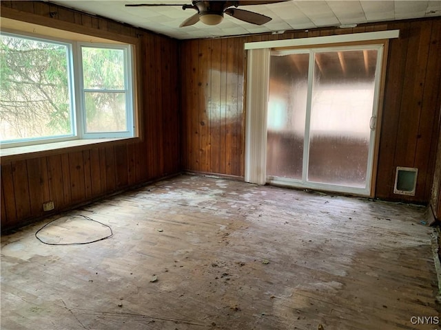 empty room with a ceiling fan and wood walls