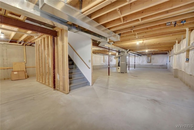 unfinished basement featuring heating unit and stairway
