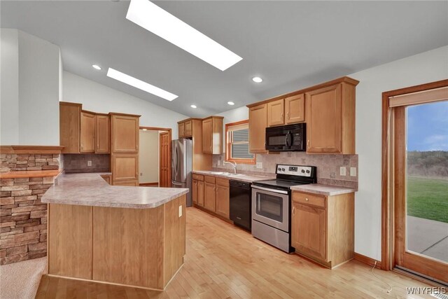 kitchen with light countertops, a sink, backsplash, and black appliances