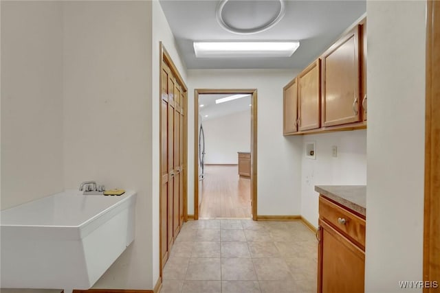 hall featuring baseboards and light tile patterned floors