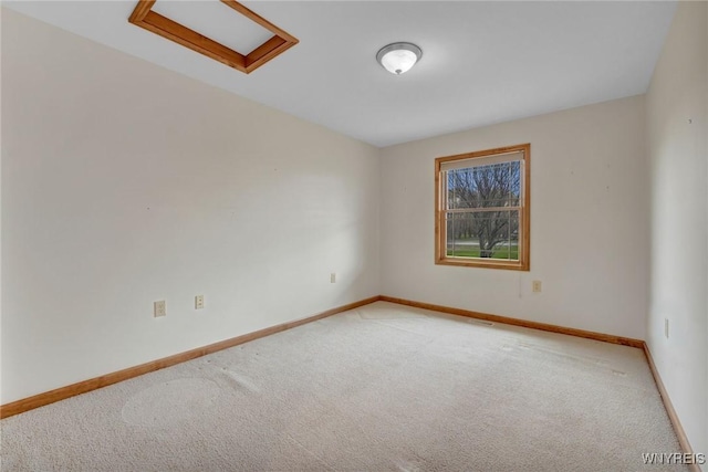 spare room featuring attic access, baseboards, and light colored carpet