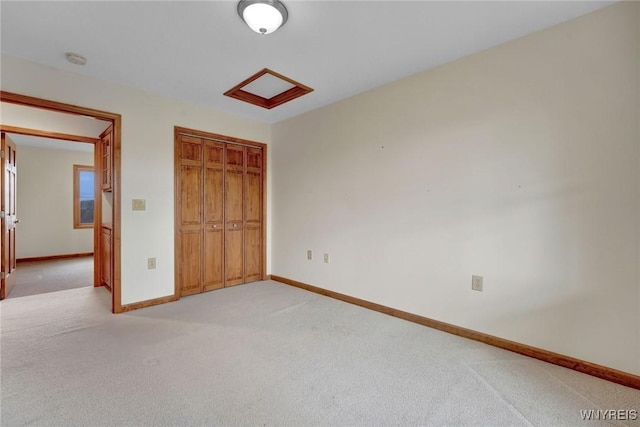 unfurnished bedroom featuring attic access, light carpet, baseboards, and a closet