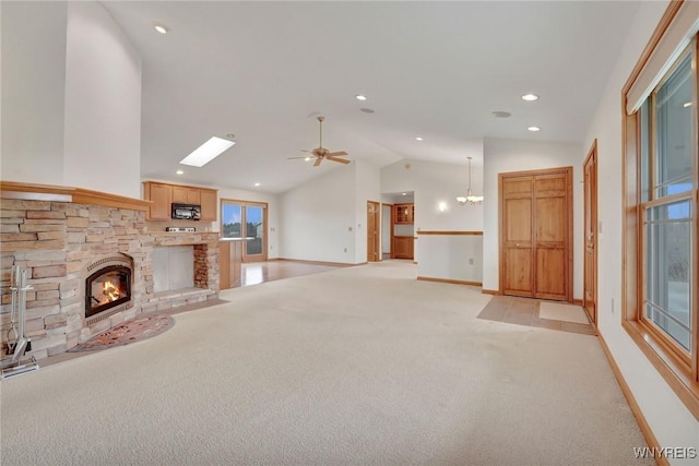 unfurnished living room featuring vaulted ceiling, a stone fireplace, a ceiling fan, baseboards, and light colored carpet