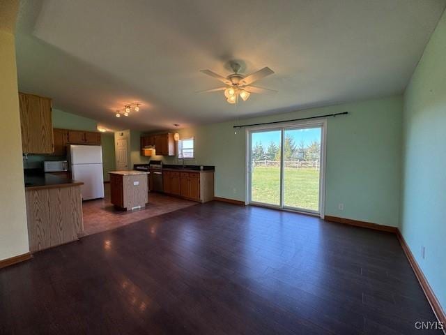 unfurnished living room with dark wood-type flooring, a ceiling fan, baseboards, and a sink