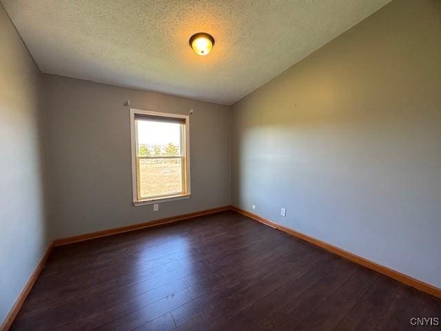 unfurnished room with baseboards, dark wood-type flooring, and a textured ceiling