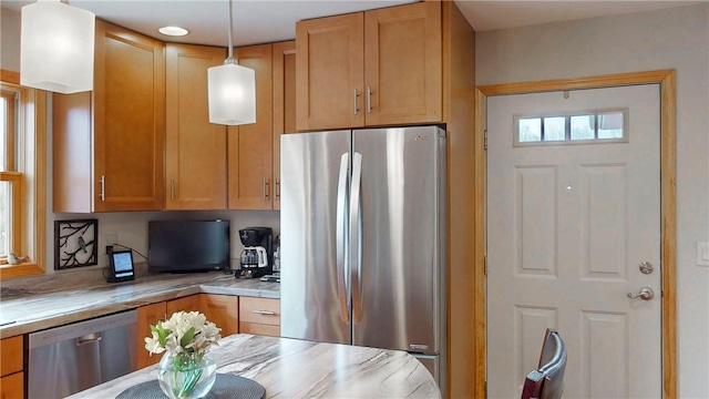 kitchen with light countertops, hanging light fixtures, appliances with stainless steel finishes, and brown cabinets