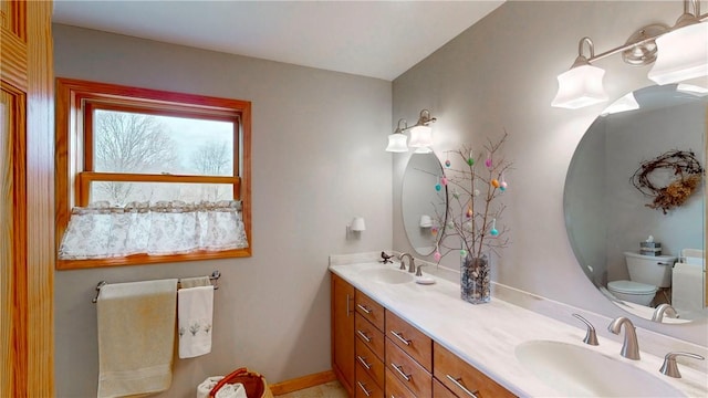 bathroom with toilet, a sink, and double vanity