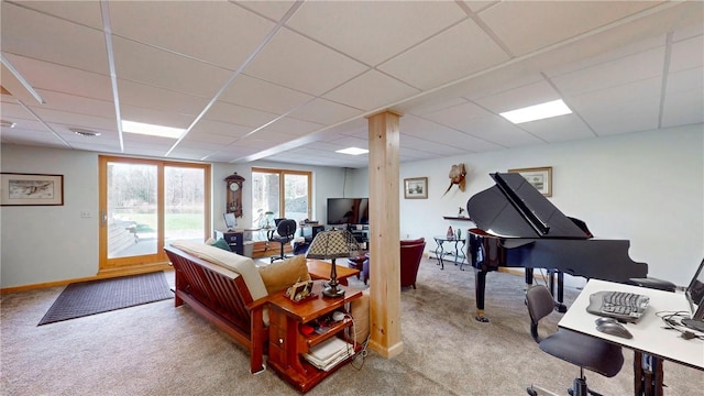 carpeted living room with a drop ceiling and baseboards