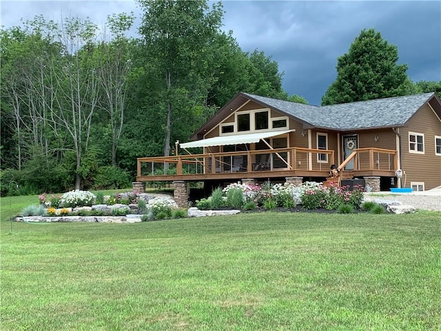 rear view of house with a wooden deck, a yard, and roof with shingles