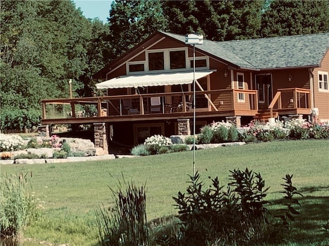 rear view of house featuring a wooden deck and a lawn