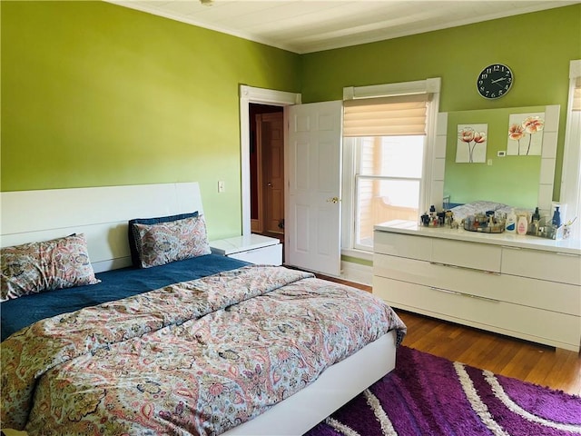 bedroom with wood finished floors and crown molding