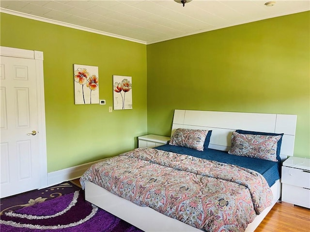 bedroom with wood finished floors, crown molding, and baseboards