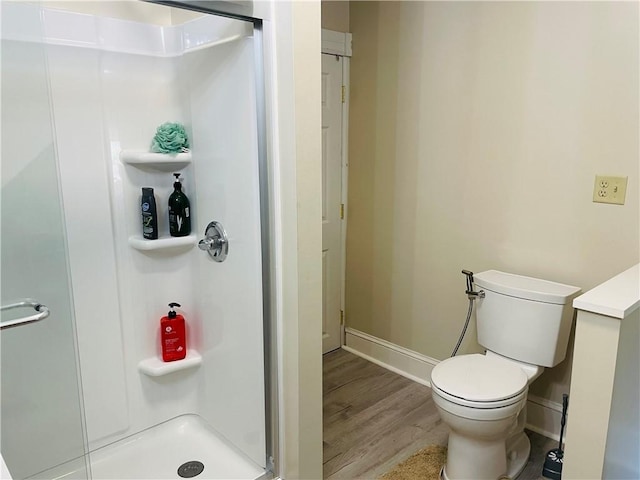 full bathroom featuring baseboards, wood finished floors, a shower stall, and toilet