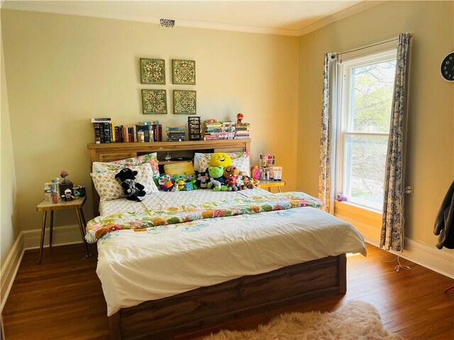 bedroom featuring baseboards, ornamental molding, and wood finished floors