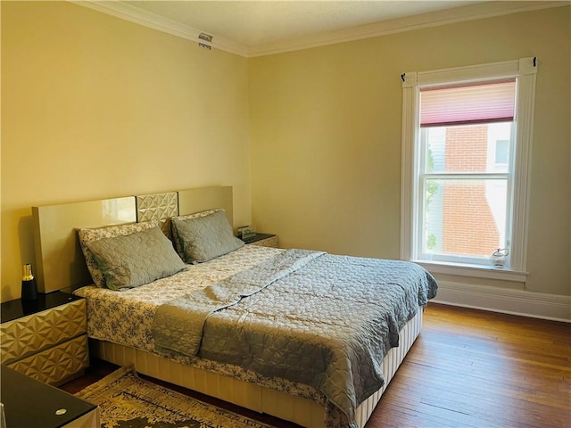 bedroom with wood-type flooring, baseboards, and ornamental molding