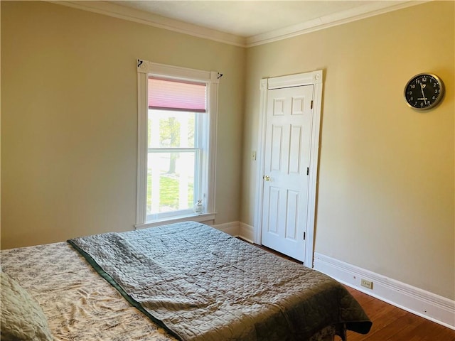 bedroom with baseboards, ornamental molding, and wood finished floors