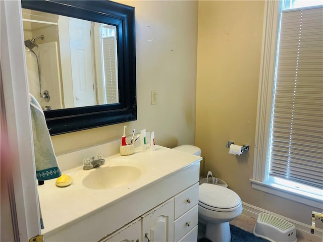 full bathroom with toilet, vanity, a shower, and baseboards