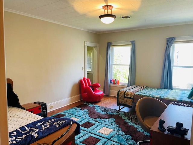 bedroom featuring baseboards, crown molding, wood finished floors, and visible vents