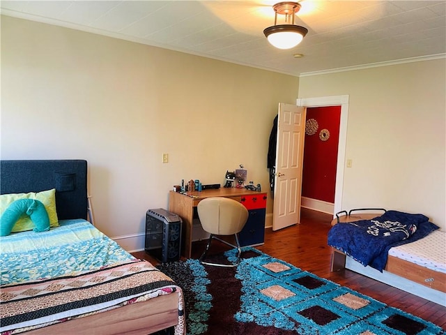 bedroom featuring baseboards, wood finished floors, and crown molding