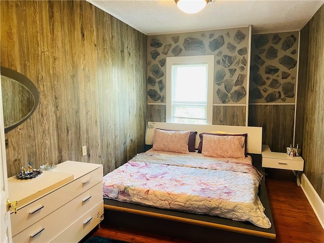 bedroom with wood walls, wallpapered walls, wood finished floors, and a textured ceiling