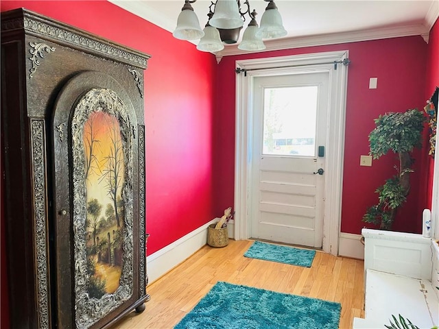 doorway to outside with an inviting chandelier, crown molding, wood finished floors, and baseboards