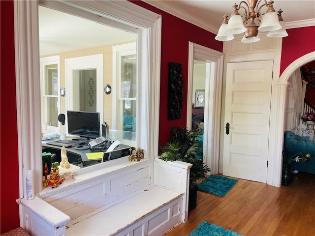 interior space featuring arched walkways, crown molding, a chandelier, and wood finished floors
