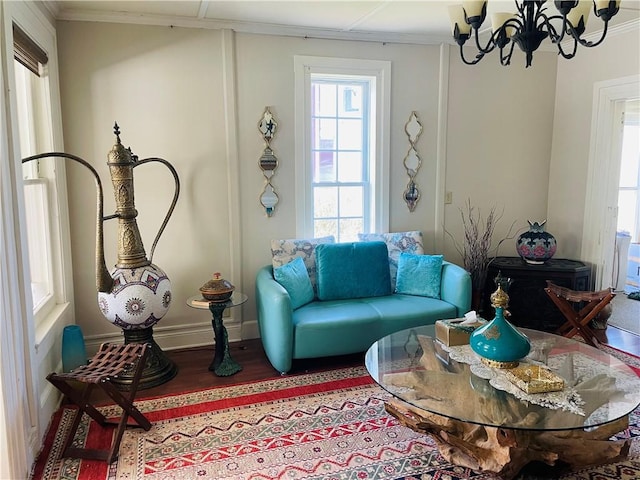 living room with ornamental molding, baseboards, a notable chandelier, and wood finished floors