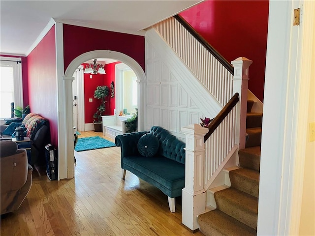 interior space with crown molding, arched walkways, stairway, and wood-type flooring
