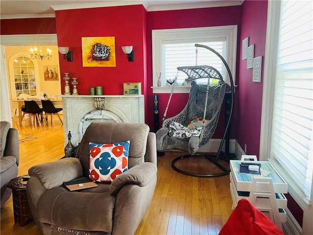 living area featuring wood-type flooring, ornamental molding, and an inviting chandelier
