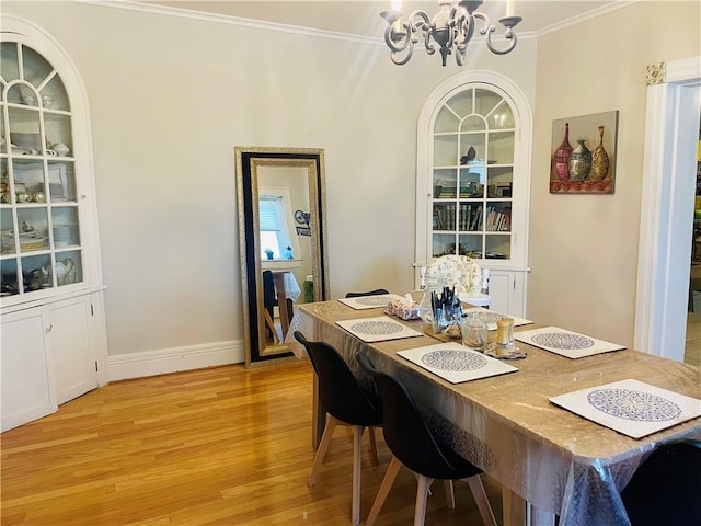 dining space featuring light wood-type flooring, baseboards, a notable chandelier, and crown molding