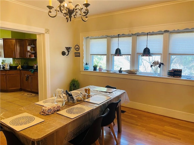 dining room featuring light wood-style flooring, baseboards, a chandelier, and crown molding