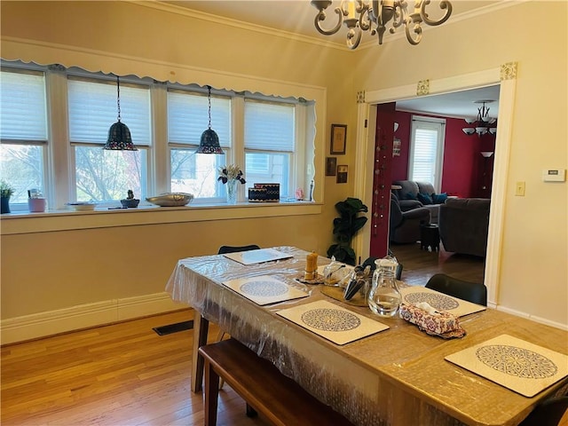 dining space featuring a chandelier, light wood-style flooring, crown molding, and baseboards