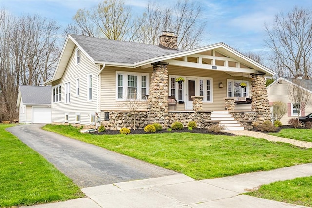 view of front of house with a chimney, a front lawn, an outdoor structure, a detached garage, and a porch