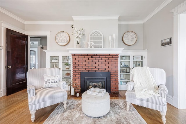 living area featuring baseboards, crown molding, a brick fireplace, and wood finished floors