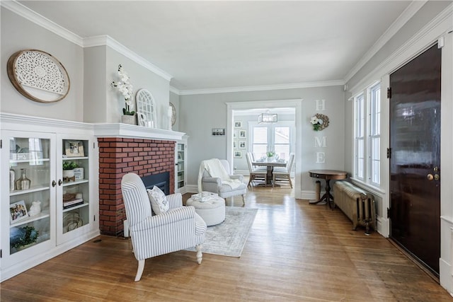 living area with radiator, crown molding, and wood finished floors