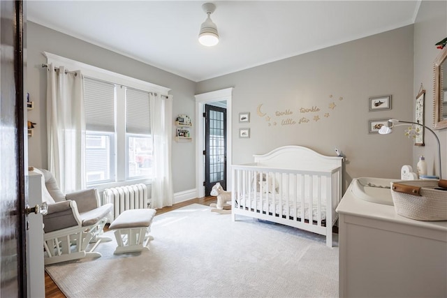 bedroom featuring baseboards, a nursery area, and radiator