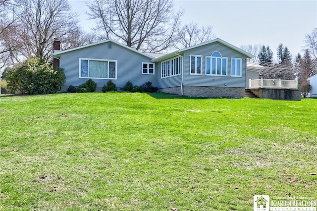 rear view of property with a lawn, a chimney, and a deck