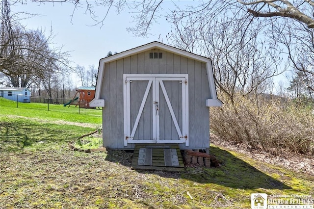 view of shed with fence and a playground