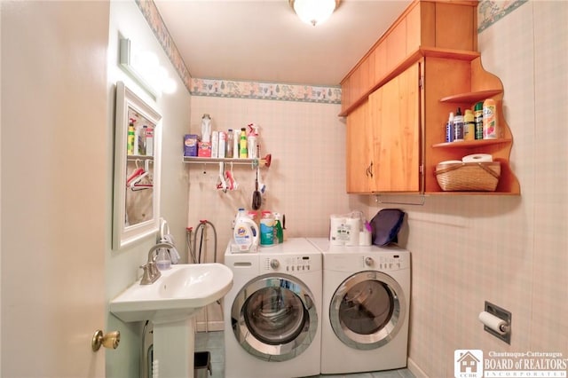 washroom featuring cabinet space, washer and clothes dryer, wallpapered walls, and a sink