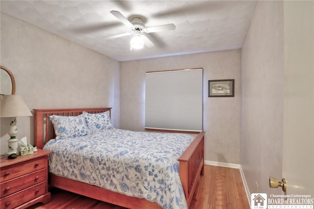 bedroom featuring wood finished floors, a ceiling fan, and baseboards